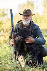 Senior hunter and his dog in forest, look for prey, hunting on wild animals. Hunting season
