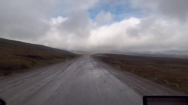 POV shot driving a truck over mud and puddles in the Dempster Highway.