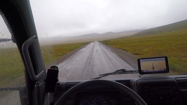 POV shot driving a camper truck during a storm on the Dempster Highway with the road covered on mud.