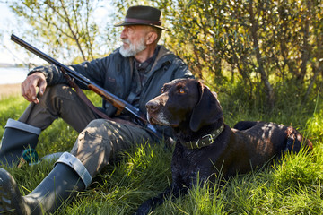 Looking for trophy with dog. Senior man ready to hunt. Sit having rest before hunting