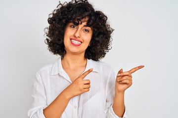 Young arab woman with curly hair wearing casual shirt over isolated white background smiling and looking at the camera pointing with two hands and fingers to the side.
