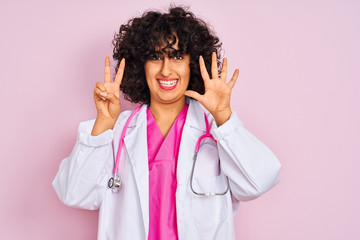 Young arab doctor woman with curly hair wearing stethoscope over isolated pink background showing...