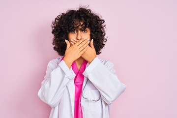 Fototapeta na wymiar Young arab doctor woman with curly hair wearing stethoscope over isolated pink background shocked covering mouth with hands for mistake. Secret concept.