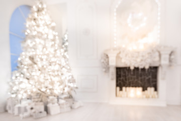 Blurred background christmas interior with New Year tree and artificial fireplace decorated light for holiday, white color