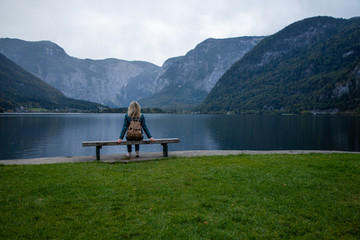 Young girl on a bench by a mountain lake enjoys the view