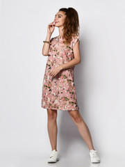 Young girl in a pink dress with floral print and sneakers.