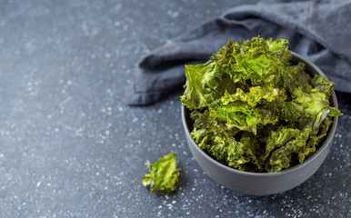Green Kale Chips with salt in bowl. Homemade healthy snack for low carb, keto, low calorie diet....