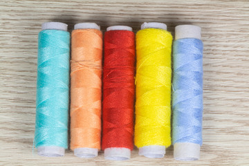 Multicolored sewing threads on wooden background