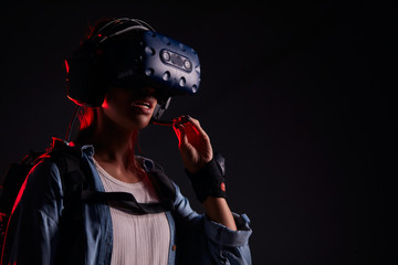 Beautiful woman wearing goggles for futuristic games stand isolated over black background