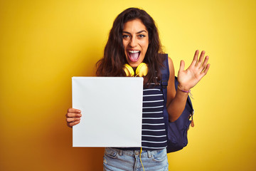 Obraz na płótnie Canvas Young beautiful student woman holding banner standing over isolated yellow background very happy and excited, winner expression celebrating victory screaming with big smile and raised hands