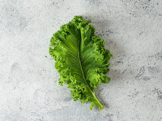 Fresh green kale leaf on gray cement background, top view. Healthy detox vegetables. Clean eating...