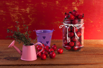 Immunity boosting treatments, infusions. Natural thyme, mint herbs and rosehip berries in a jar on a wooden background.