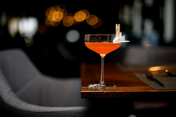 Orange cocktail drink in the glass decorated with a paper airplane in the clothespin