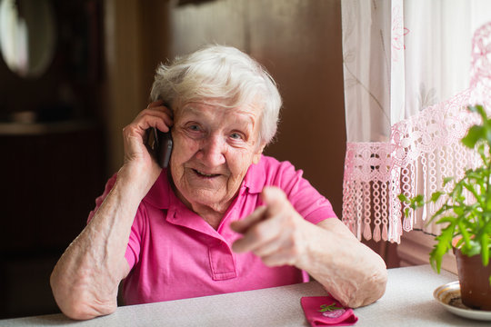 Elderly woman talks on a mobile phone and gestures.