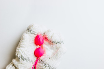 Christmas or New Year composition. Pink sex toy in female hands in knitted mittens on white background. Top view. Copy space. Flat lay. Christmas minimal concept.
