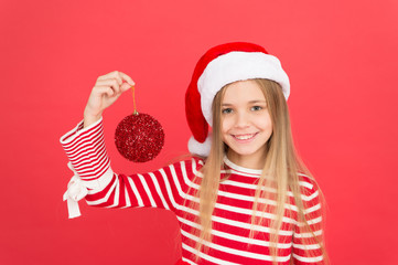 Decorate Christmas with joy. Little santa girl hold Christmas tree ball. Happy child smile with red glitter ball. Christmas bauble or ball ornament. Fragile glass ball decoration. Xmas bulb or bauble