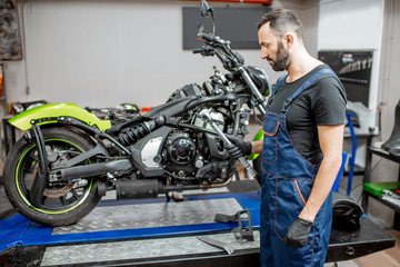 Fototapeta na wymiar Mechanic repairing motorcycle at the workshop