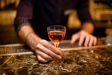 Professional male bartender serving a short cocktail in the little glass