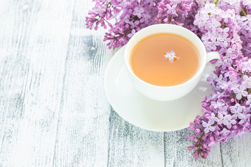 Cup of herbal tea and lilac on wooden background. Rays of sunlight - Image