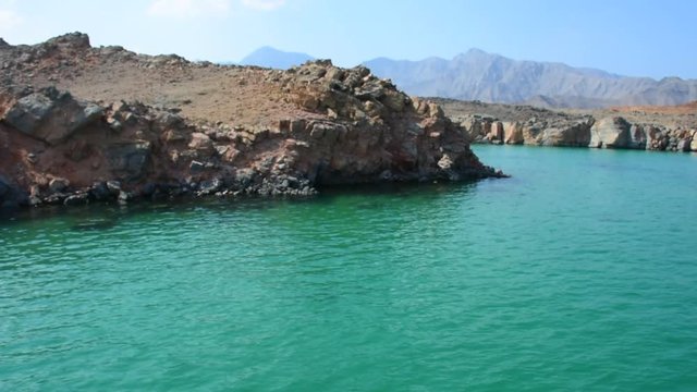 Green waters of Musandam, Oman on a Dhow Boat trip in the Middle East the fjords, rocky mountains, and blue water near Strait of Hormuz 