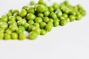 On a white background scattered with fresh green peas, there is a place for an inscription.