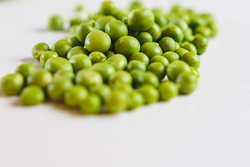 On a white background scattered with fresh green peas, there is a place for an inscription.