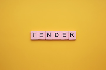 Tender word wooden cubes on an yellow background.