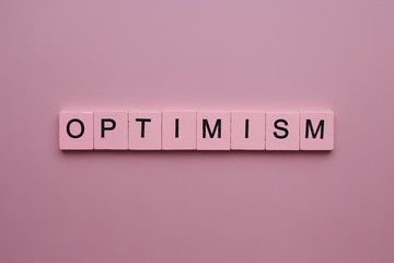 Optimism word wooden cubes on pink background