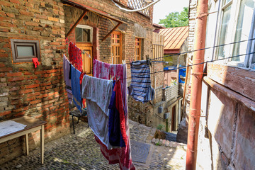 A typical georgian yard of an old traditional wooden house and clothes and linen drying on the ropes. Tbilisi Georgia, Caucasus mountains