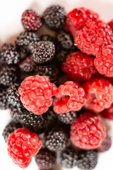 Fresh berries of sweet red and black raspberries on a white background.