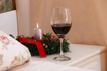 At Christmas, Santa Claus sits with a gift near the bed next to a burning candle.