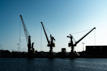 Obraz premium silhouette of port cranes in a large commercial port under a blue evening sky at twilight