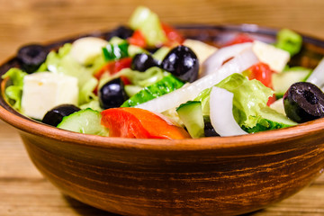 Ceramic plate with greek salad on wooden table