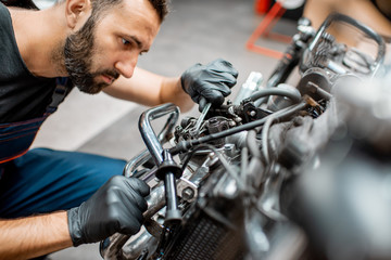 Worker repairing motorcycle engine at the workshop
