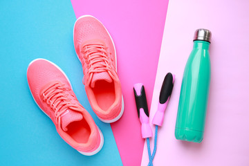 Sports water bottle, shoes and jumping rope on color background - obrazy, fototapety, plakaty