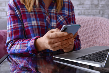 Woman with laptop using mobile phone at table, closeup
