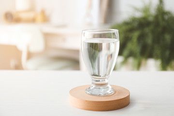 Glass of fresh water on table in room