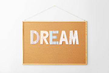 Board with word DREAM on white background