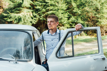 Portrait elegant fiance in a white shirt. Man standing near old car