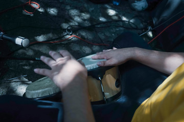 Sitting playing congas outside. Drum between the legs. African drums. Percussion instrument being played concept. Represented by percussionists hands hitting a drum.