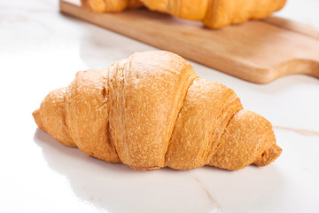 Sweet tasty croissant on light background