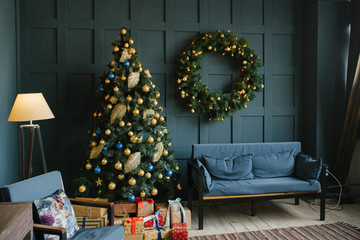 Blue sofa with pillows and Christmas wreath on the wall in the living room in the loft style.