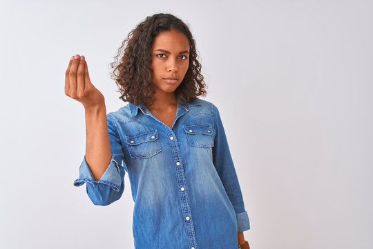 Young brazilian woman wearing denim shirt standing over isolated white background Doing Italian gesture with hand and fingers confident expression
