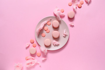 Plate with tasty macarons and sweets on color background