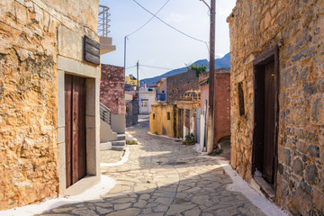 Fototapeta na wymiar Narrow street with colorful stone houses in the old village of Pano Elounda, Crete, Greece. 