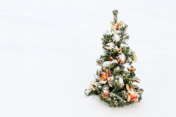 Dressed with a variety of decorations, the Christmas tree is sprinkled with snow with copyspace.