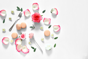 Tasty macarons with rose flowers on white background