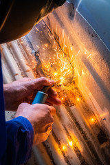 Man welds in metal of car and repairs rusty hole