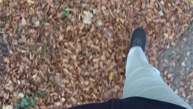 Sicht auf Beine und F&uuml;&szlig;e die &uuml;ber einen Laubboden gehen
