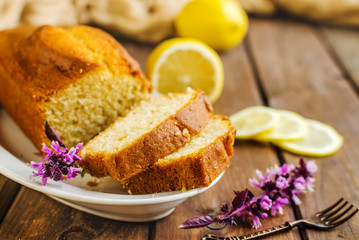 Lemon pound cake on rustic wooden background with lemon.